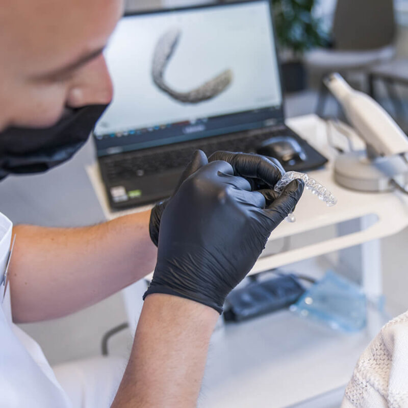a dentist holding a clear aligner tray to be fitted for a patient