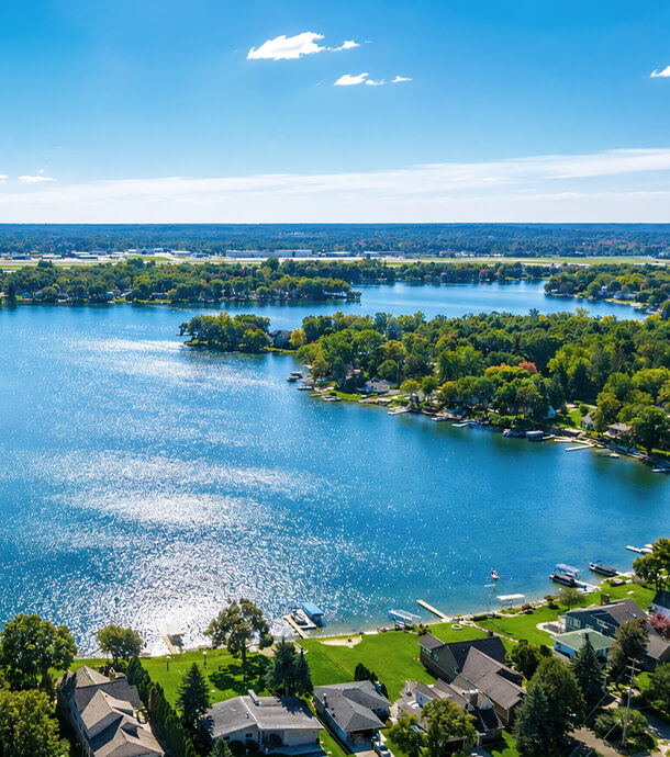 photograph of suburb with calm lake, trees and houses