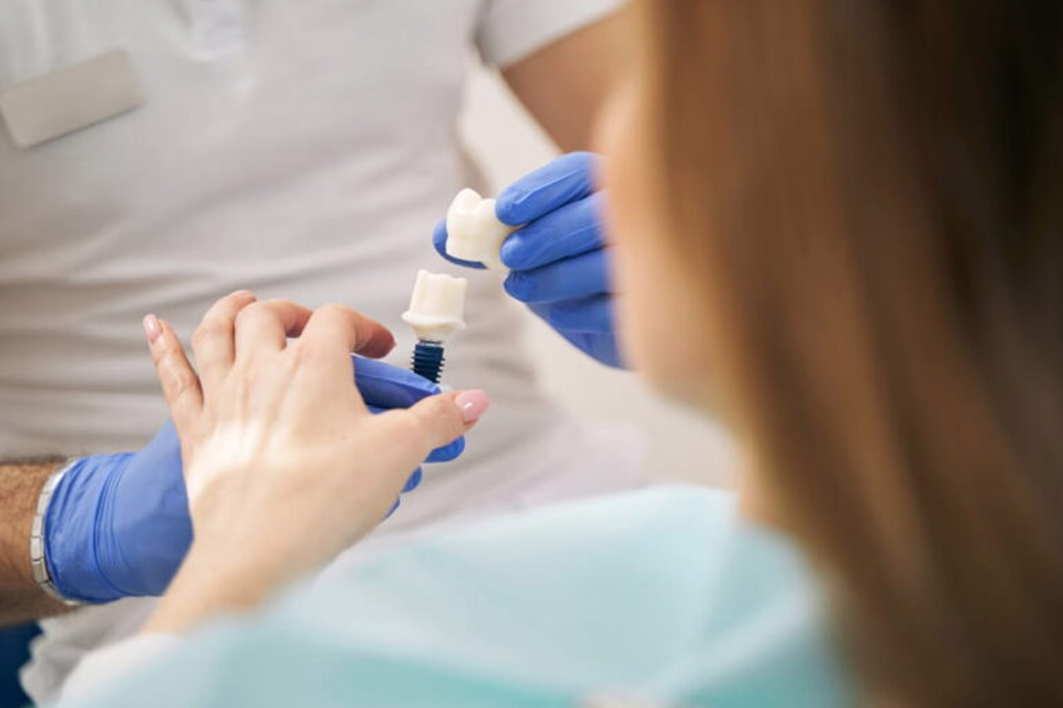 Dentist showing dental implant to woman in clinic