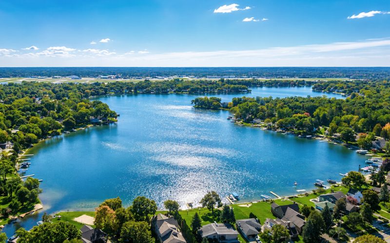 photograph of suburb with calm lake, trees and houses